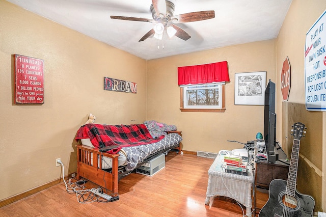 bedroom featuring ceiling fan, wood finished floors, and baseboards