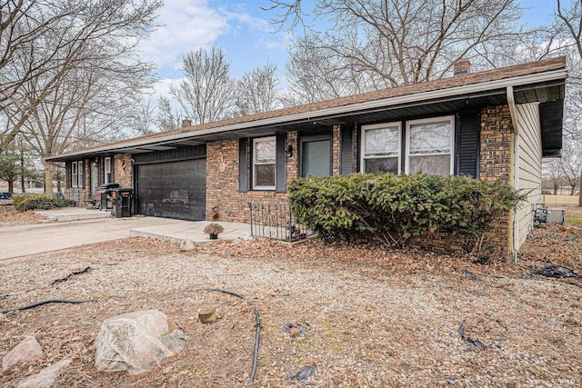 view of front of property featuring concrete driveway, brick siding, a chimney, and an attached garage