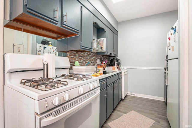 kitchen featuring light wood finished floors, light countertops, gray cabinetry, decorative backsplash, and white appliances