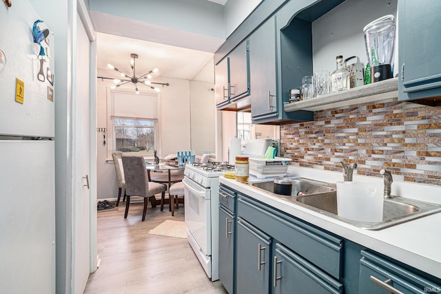 kitchen with white appliances, tasteful backsplash, a notable chandelier, light wood-type flooring, and a sink