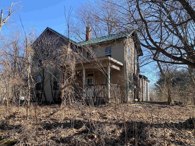 view of front of property with covered porch, metal roof, and a chimney