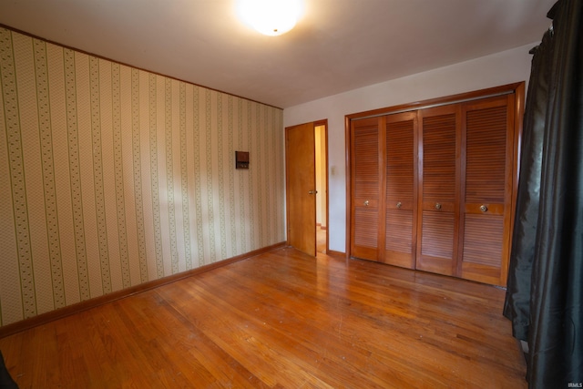 unfurnished bedroom featuring baseboards, light wood finished floors, and wallpapered walls