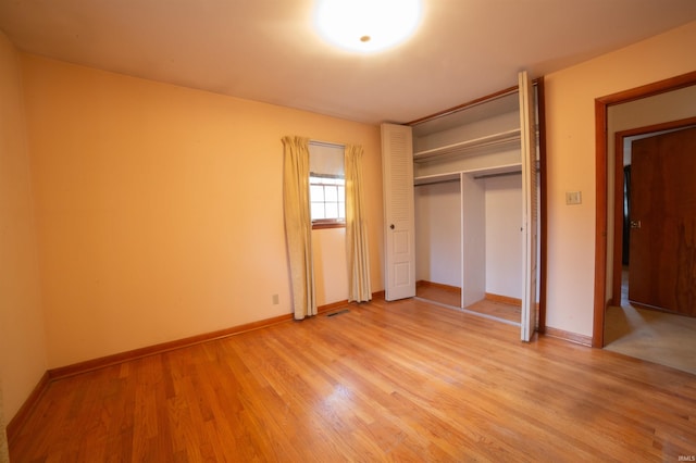 unfurnished bedroom featuring light wood finished floors, a closet, visible vents, and baseboards