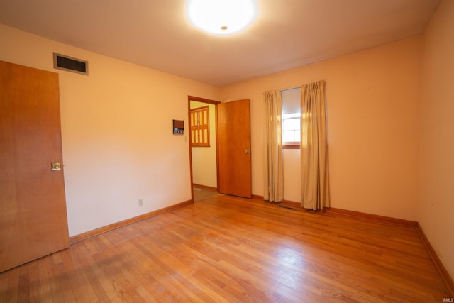 spare room featuring wood finished floors, visible vents, and baseboards