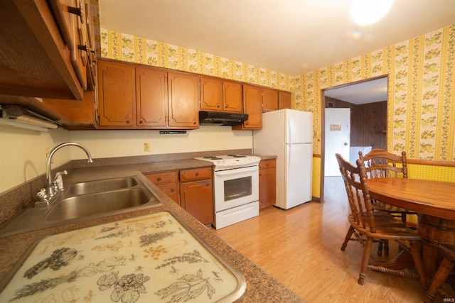 kitchen featuring under cabinet range hood, white appliances, a sink, light wood-style floors, and wallpapered walls