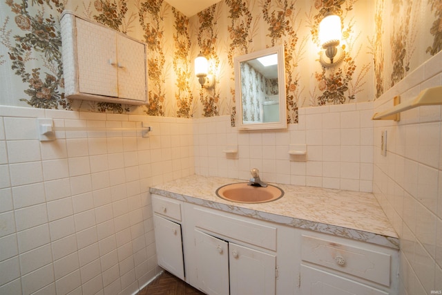 bathroom with wallpapered walls, vanity, and wainscoting