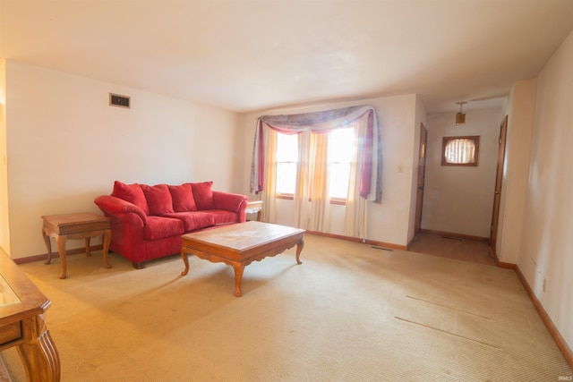 living area featuring baseboards, visible vents, and light colored carpet