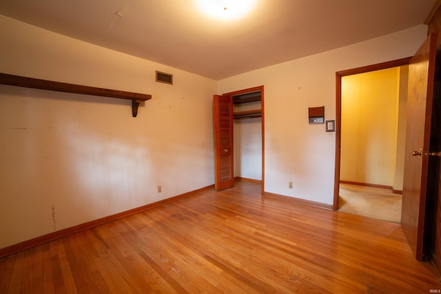 unfurnished bedroom with baseboards, light wood-style flooring, visible vents, and a closet