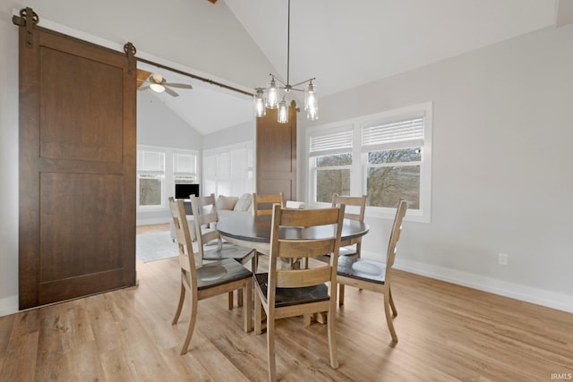 dining area featuring light wood-style floors, baseboards, and high vaulted ceiling