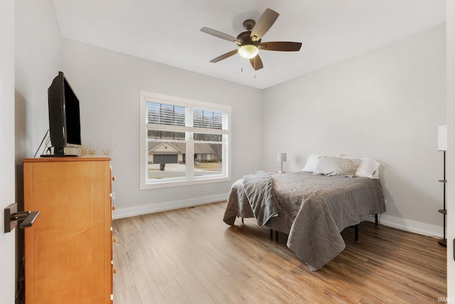 bedroom featuring a ceiling fan, light wood-style flooring, and baseboards