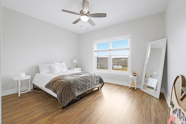 bedroom with visible vents, ceiling fan, baseboards, and wood finished floors