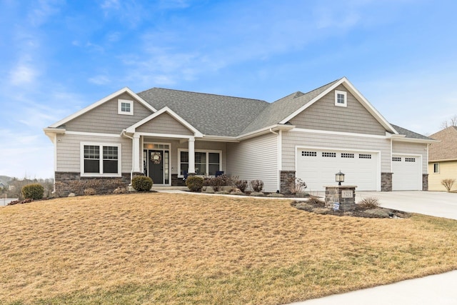 craftsman-style home featuring a front yard, stone siding, an attached garage, and concrete driveway