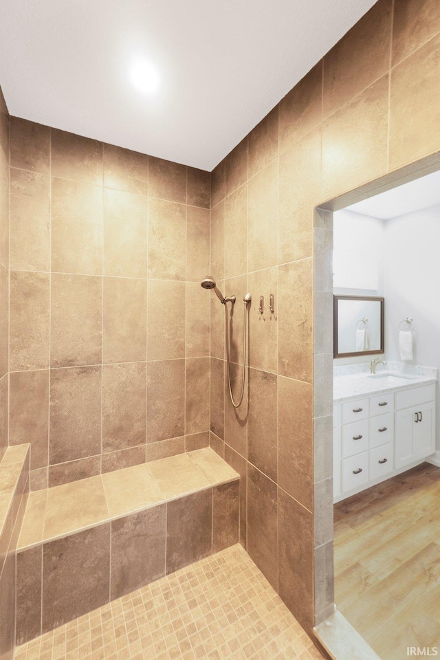 bathroom featuring a tile shower, wood finished floors, and vanity