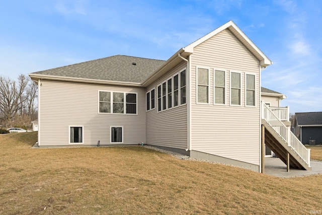 back of house with stairs, a yard, and a shingled roof