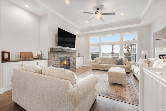 living room with a stone fireplace, wood finished floors, and crown molding