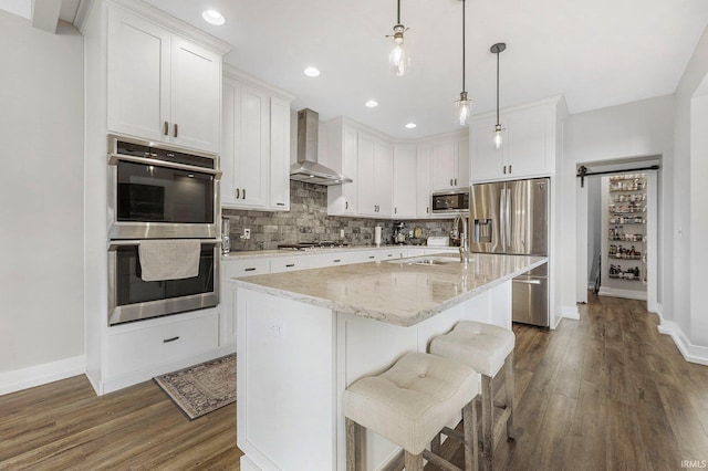 kitchen featuring dark wood-style flooring, a sink, stainless steel appliances, wall chimney range hood, and backsplash