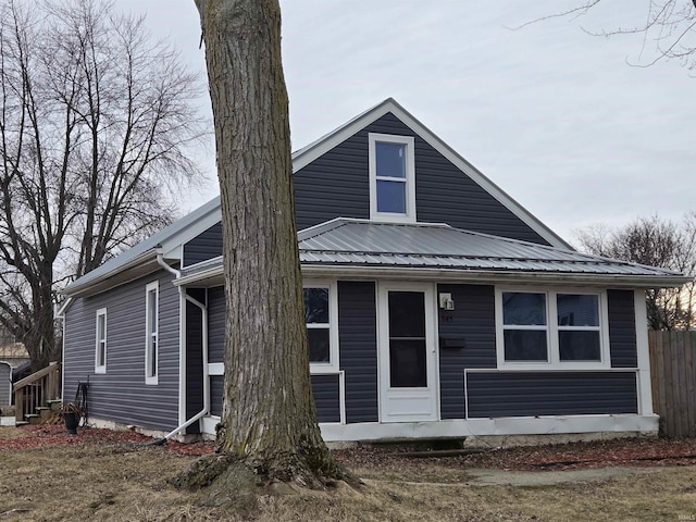 view of front of property featuring metal roof and fence