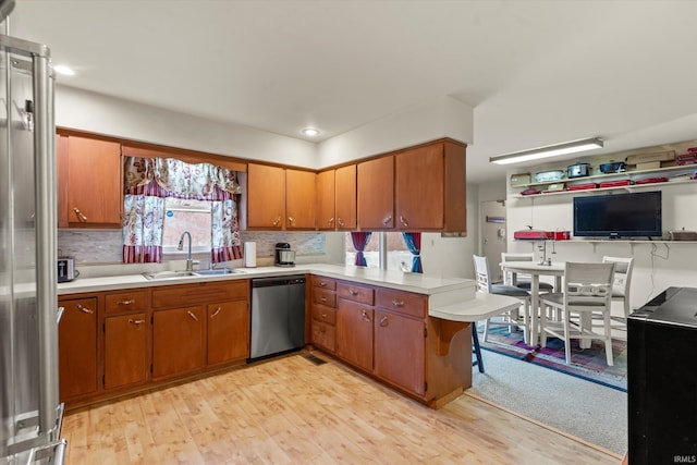 kitchen with dishwasher, light countertops, a peninsula, and a sink