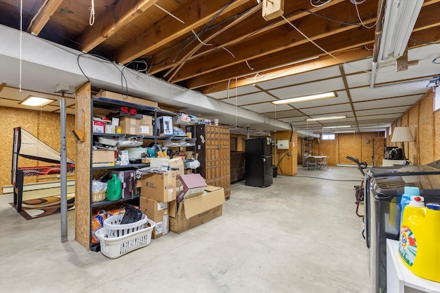 unfinished below grade area featuring baseboard heating and freestanding refrigerator