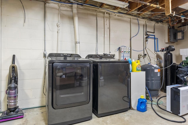 laundry room with washing machine and dryer, laundry area, electric panel, and concrete block wall