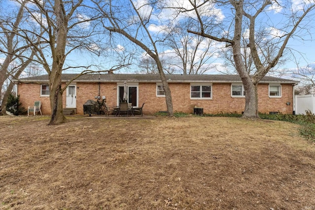 view of front facade with fence, a front lawn, a patio, and brick siding