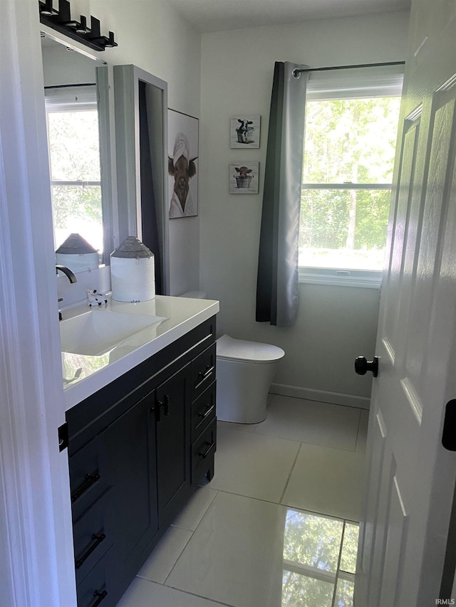 bathroom featuring toilet, tile patterned flooring, baseboards, and vanity