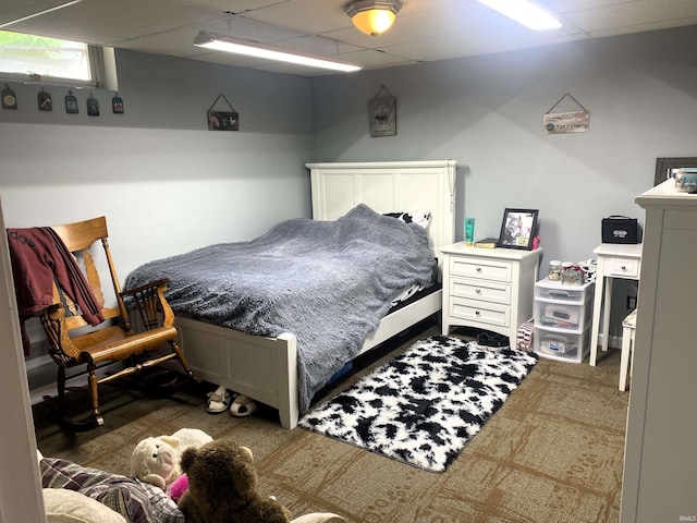 carpeted bedroom featuring a drop ceiling