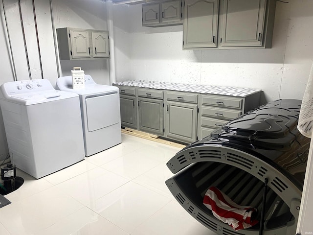 washroom with cabinet space, washing machine and clothes dryer, and light tile patterned floors