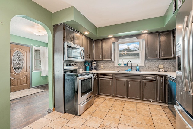 kitchen with light tile patterned floors, tasteful backsplash, stainless steel appliances, and a sink