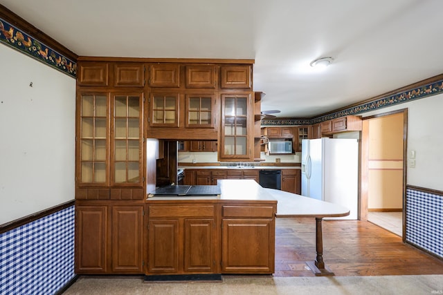 kitchen featuring glass insert cabinets, brown cabinets, a peninsula, and black appliances