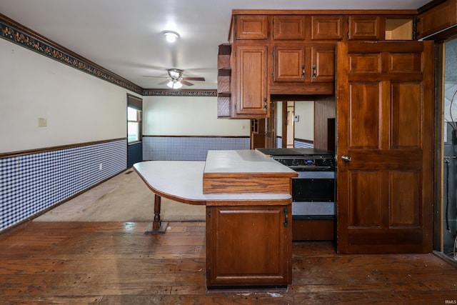 kitchen with dark wood-style floors, brown cabinets, a wainscoted wall, open shelves, and a ceiling fan