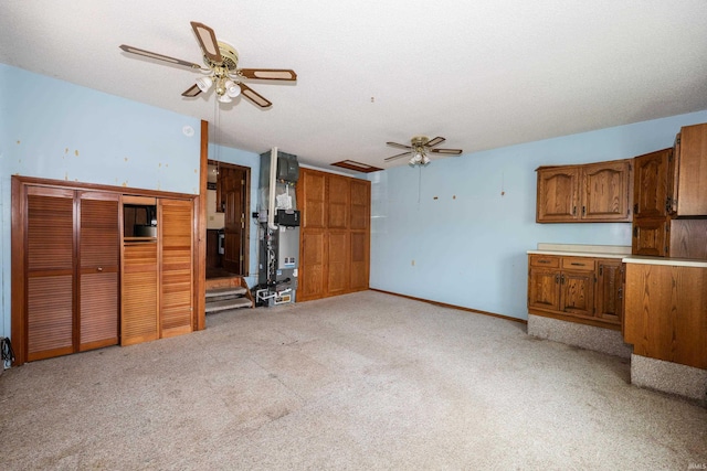 unfurnished living room with a textured ceiling, baseboards, a ceiling fan, and light colored carpet