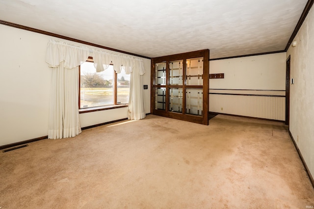 carpeted spare room with visible vents, crown molding, a textured ceiling, and baseboards