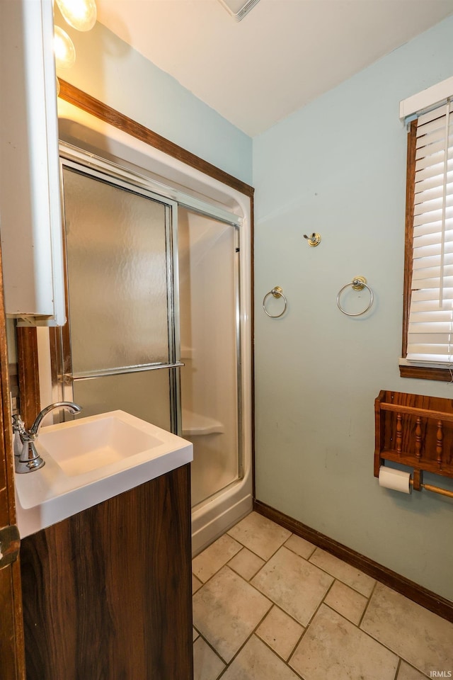 bathroom with a shower with door, a sink, and baseboards