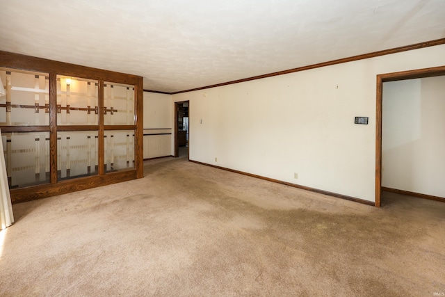 carpeted empty room with crown molding and baseboards