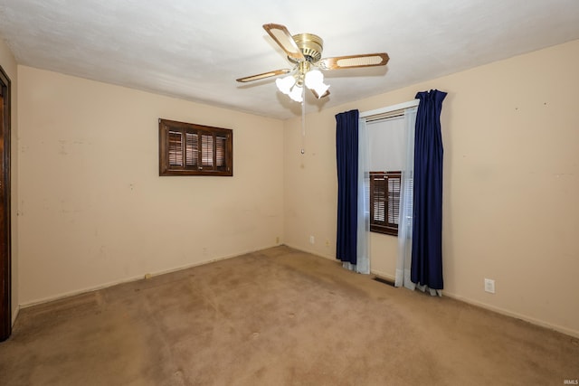 carpeted spare room featuring a ceiling fan, visible vents, and baseboards