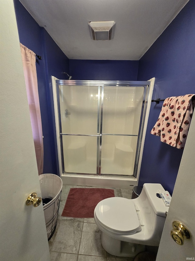 bathroom featuring toilet, a shower stall, and visible vents