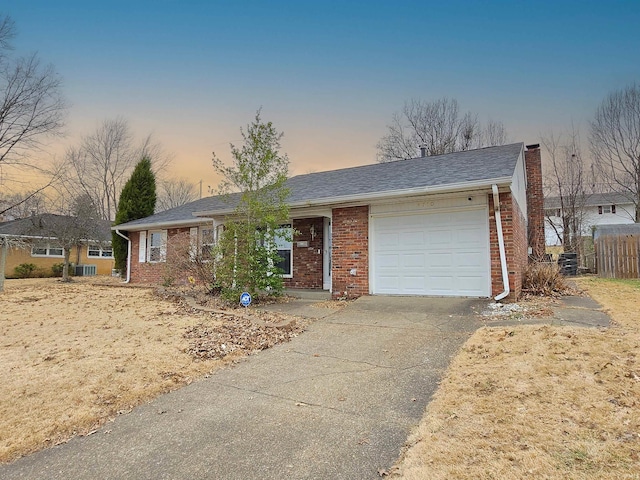 single story home with a garage, driveway, a chimney, roof with shingles, and brick siding