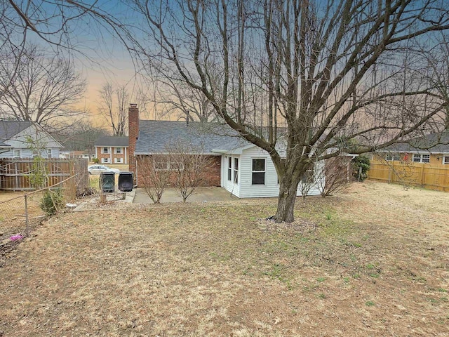 back of house featuring a patio area, a fenced backyard, a lawn, and a chimney