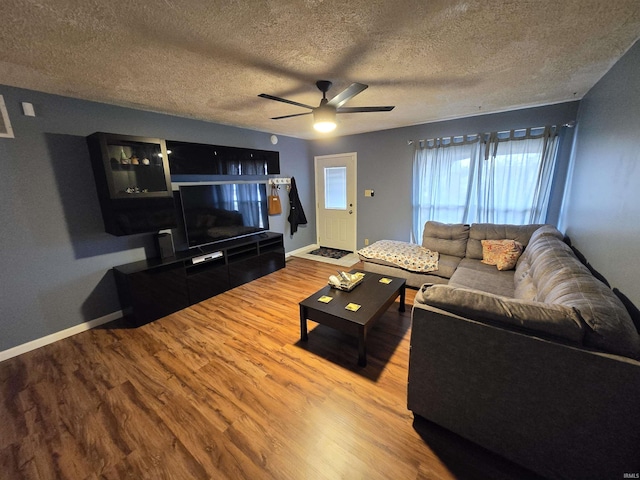 living room featuring a textured ceiling, wood finished floors, a ceiling fan, and baseboards