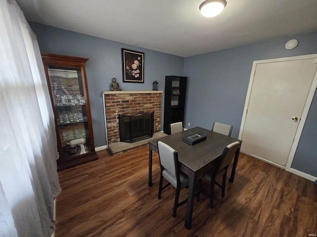 dining area featuring a fireplace, baseboards, and wood finished floors