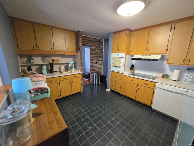 kitchen with dark floors, light countertops, brick wall, white appliances, and under cabinet range hood