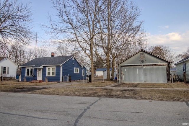 view of front of property featuring a chimney, roof with shingles, an outdoor structure, and a garage