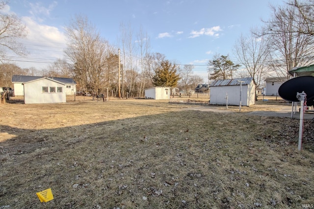 view of yard featuring a shed, an outdoor structure, and fence