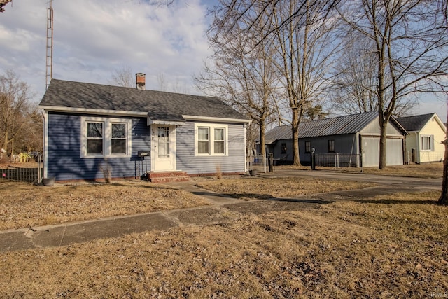 view of front of home with a shingled roof, a chimney, and fence