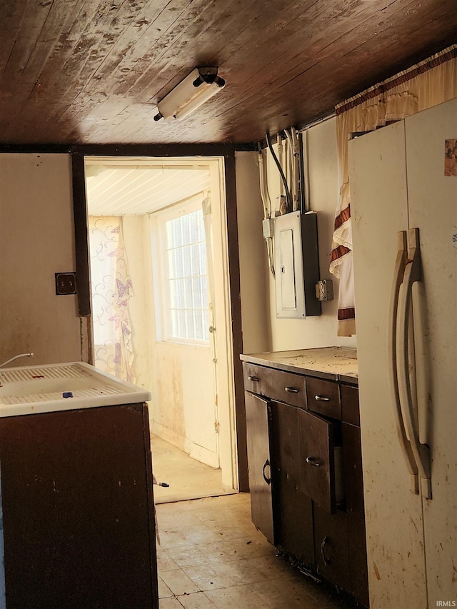 kitchen with freestanding refrigerator, wood ceiling, electric panel, and dark brown cabinets