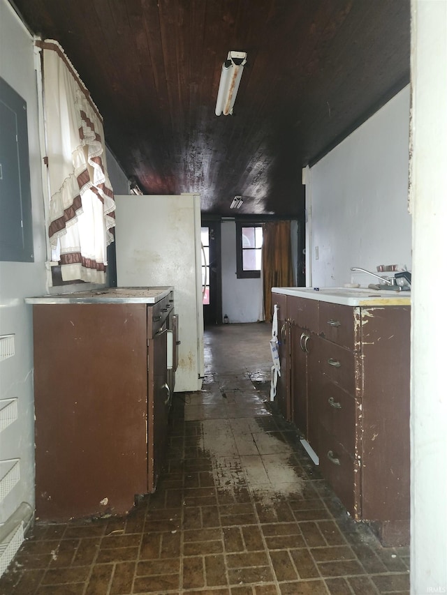 kitchen with brick floor, light countertops, wood ceiling, dark brown cabinetry, and a sink