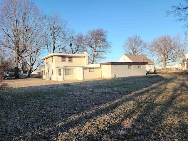 rear view of property with a lawn and a chimney