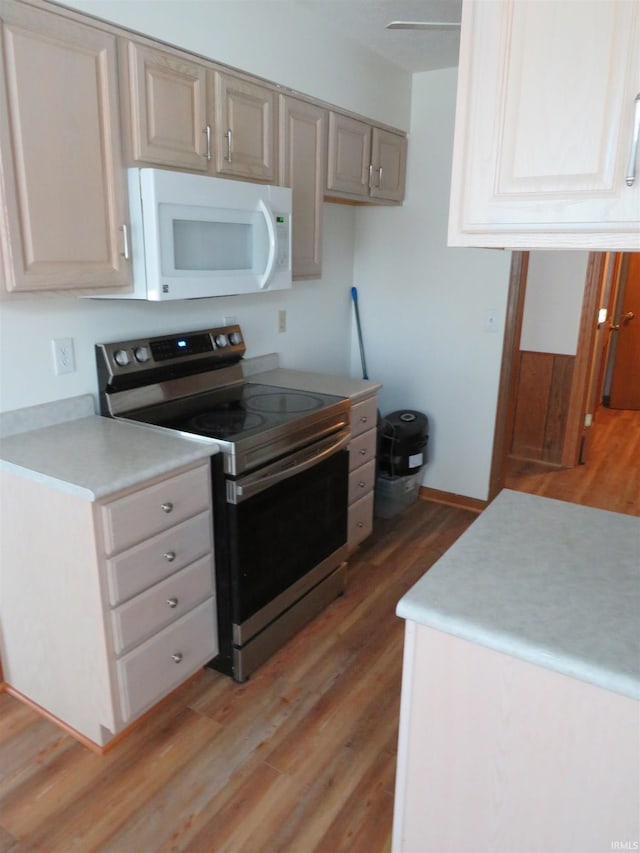 kitchen with stainless steel range with electric stovetop, light wood-type flooring, and white microwave