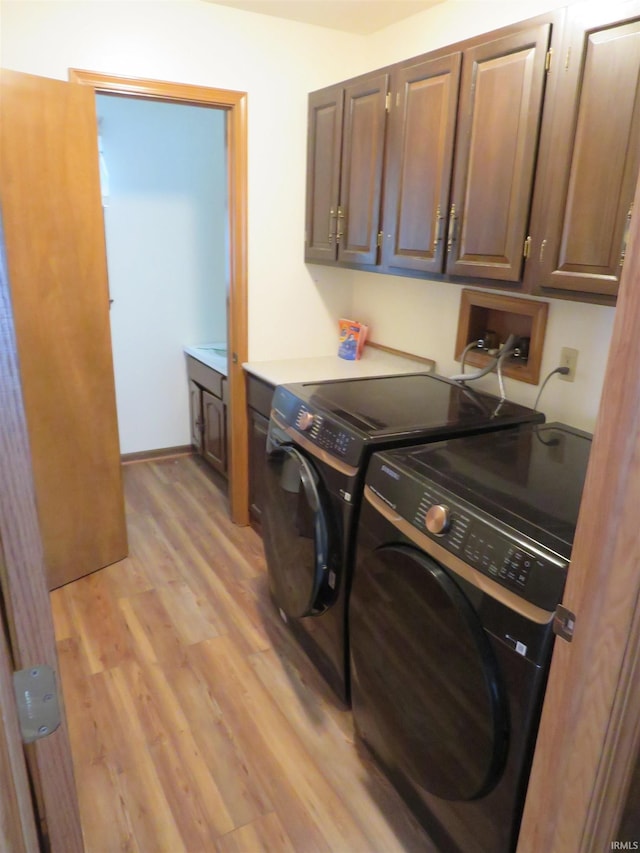 washroom with cabinet space, light wood-style floors, and washer and dryer